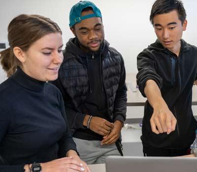 3名学生围着一台笔记本电脑